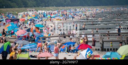 14 juillet 2021, Mecklembourg-Poméranie occidentale, Zingst: À la plage de la mer Baltique en face de la jetée, de nombreux baigneurs se sont installés à 26 degrés de température de l'air sur la plage. Photo: Stefan Sauer/dpa Banque D'Images