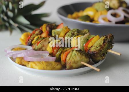 Kebab au poulet et à l'ananas. Un plat de morceaux de poulet et de poivrons marinés avec du masala à la coriandre et des tranches d'ananas grillées sur une brochette Banque D'Images