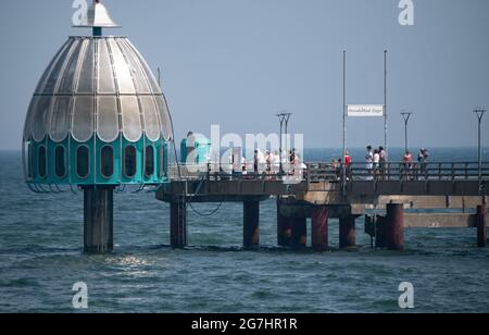 Zingst, Allemagne. 14 juillet 2021. Les touristes marchent en face de la télécabine de plongée sur la jetée de l'Ostseebad Zingst. Credit: Stefan Sauer/dpa/Alay Live News Banque D'Images