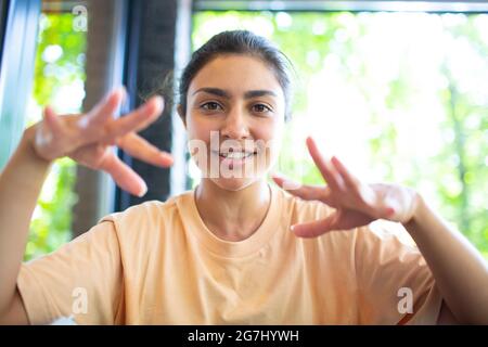 Plan de tête de femme indienne s'asseoir sur le café de potdoor en agitant la main regarde à la caméra faire appel vidéo chat utiliser ordinateur portable webcam vue, vlogger record webinar entretien de travail concept distly. Banque D'Images