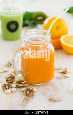 Portrait de jus d'orange en verre, fruits à coque et fruits frais sur fond de bois. Banque D'Images