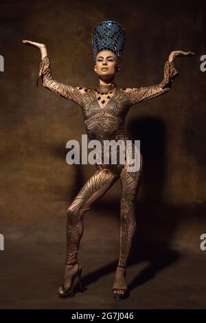 Jeune femme à l'image de Nefertiti dans l'art performance isolée sur fond brun vintage. Style rétro, comparaison du concept ERAS. Banque D'Images