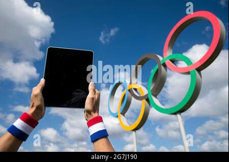 RIO DE JANEIRO - AVRIL 2016 : athlète portant un bracelet rouge, blanc et bleu touchant l'écran d'une tablette informatique devant les anneaux olympiques Banque D'Images