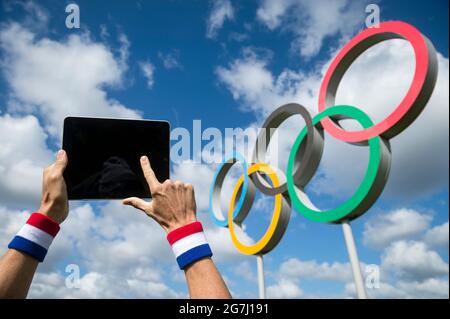 RIO DE JANEIRO - AVRIL 2016 : athlète portant un bracelet rouge, blanc et bleu touchant l'écran d'une tablette informatique devant les anneaux olympiques Banque D'Images