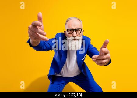 Photo de malheureux colère vieux homme vous point strict porter des lunettes bleu costume isolé sur fond jaune brillant Banque D'Images