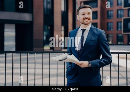 Un employé de bureau heureux en pause debout tout en tenant le journal Banque D'Images