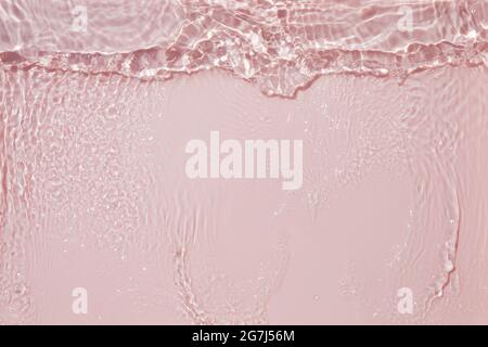 Texture rose de la surface de l'eau claire avec des éclaboussures et des bulles.Arrière-plan d'eau abstrait tendance.Vagues d'eau sous la lumière du soleil. Banque D'Images