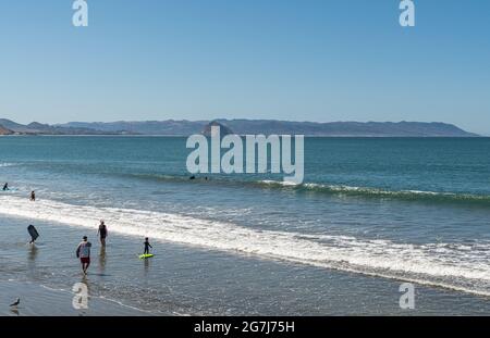 Cayucos, CA, USA - 10 juin 2021: Vue sur Morro Rock dans la baie de Morro depuis la jetée de Cayucos. Blue Pacific Ocean plante avec le surf blanc sur la plage avec b Banque D'Images