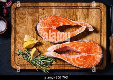 Steaks de saumon. Tranches de saumon frais avec épices, herbes et citron sur planche à découper en bois, vue du dessus Banque D'Images