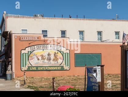 Cayucos, CA, Etats-Unis - 10 juin 2021 : peinture murale colorée de cowboy à l'extérieur de la cardroom de la taverne Old Cayucos. Vue sur la rue du bâtiment sous Blue sk Banque D'Images