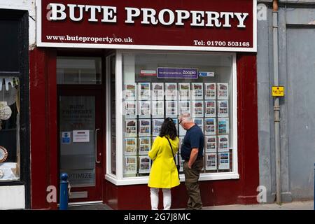 Deux membres SO f public regardant des maisons à vendre dans le vent OW de l'agence immobilière à Rothesay , île de Bute, Ecosse, Royaume-Uni Banque D'Images