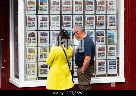 Deux membres SO f public regardant des maisons à vendre dans le vent OW de l'agence immobilière à Rothesay , île de Bute, Ecosse, Royaume-Uni Banque D'Images