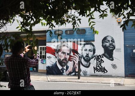 Londres, Royaume-Uni. 14 juillet 2021. Un passant prend des photos de la fresque du Manager de football d'Angleterre Gareth Southgate et des joueurs Harry Kane et Raheem Sterling, avec les mots « You DID US Proud », est vu sur un mur à Vinegar Yard à Londres. La fresque a été peinte par MurWalls à la suite de la réussite de l'équipe de football d'Angleterre qui a atteint la finale de l'Euro 2020. (Photo de Hesther ng/SOPA Images/Sipa USA) crédit: SIPA USA/Alay Live News Banque D'Images