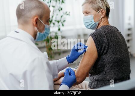 la femme dans un masque de protection est vaccinée dans un bureau médical. Banque D'Images