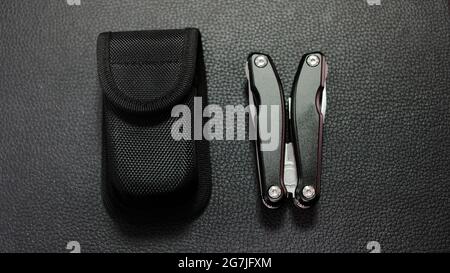 MultiTool avec boîtier noir sur fond en cuir noir Banque D'Images