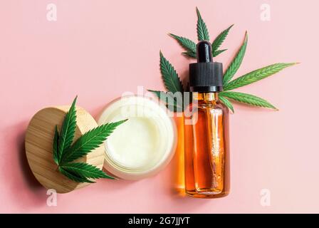 CBD bouteilles d'huile de cannabis crème de soin pour la peau de chanvre et feuilles de cannabis sur fond rose Banque D'Images