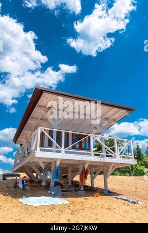 Cabine de sauveteur blanche en bois située sur une plage de sable, dans un ciel bleu et nuageux Banque D'Images