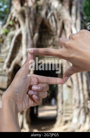 Les mains des touristes imitent la photographie dans le complexe du temple khmer d'Angkor au Cambodge. Banque D'Images