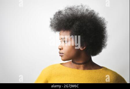 Profil latéral d'une jeune femme noire aux cheveux bouclés courts portant un chandail jaune Banque D'Images