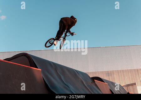 BMX rider faire le tour sur la rampe dans le parc de skate. Sports, sports extrêmes, freestyle, le concept de l'activité en plein air. Banque D'Images