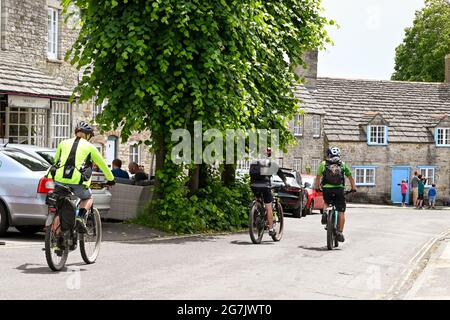 Château de Corfe, Dorset, Angleterre - juin 2021 : groupe de cyclistes qui traversent l'une des rues de maisons traditionnelles du village de Corfe Castle Banque D'Images