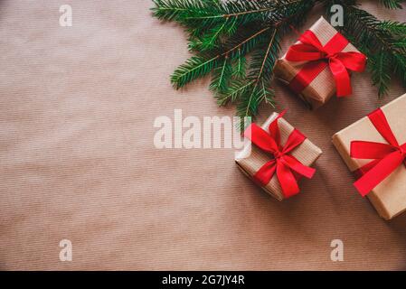 Arrière-plan des fêtes de Noël et du nouvel an. Branches d'arbre de Noël, boîtes-cadeaux avec ruban rouge sur fond de papier artisanal. Vue sur le dessus, plan d'eau, Copy spa Banque D'Images