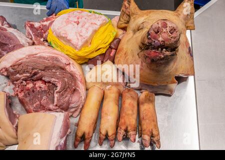 Tête et pattes d'un porc sur le comptoir d'une boucherie sur le marché d'un fermier, gros plan de la carcasse de porc bouchées. Banque D'Images