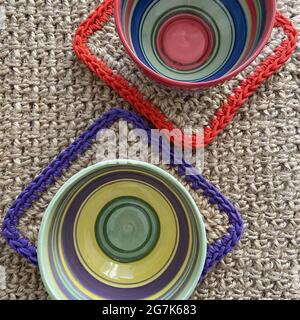 Vue verticale sur le dessus de jolies tasses colorées sur des sets de table tissés à la main Banque D'Images