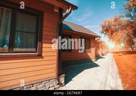 Plan grand angle d'un groupe de maisons en bois similaires d'une auberge de jeunesse ou d'un camping s'étendant au loin avec un sentier asphalté juste en dessous Banque D'Images
