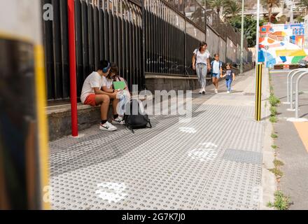 Des camarades de classe caucasiens attendent à l'arrêt de bus de l'école Banque D'Images