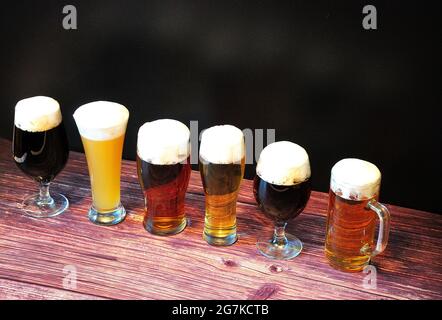 Six verres avec bière de différentes variétés, se tiennent sur une table en bois. Gros plan. Banque D'Images