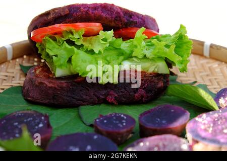 Délicieux hamburger végétalien de patate douce violette à la tomate, salade, nourriture saine pour le petit déjeuner que l'amidon riche, la fibre sur fond blanc Banque D'Images