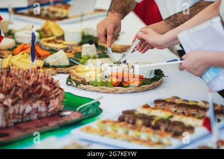 Image de faible profondeur de champ (mise au point sélective) avec des personnes mangeant des apéritifs de cuisine française à partir d'une table. Banque D'Images