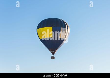 Le ballon d'air chaud vole sur un ciel bleu.un ballon d'air chaud bleu jaune dans un ciel bleu clair. Banque D'Images