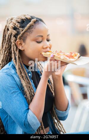 Belle femme afro-américaine prenant un morceau de pizza délicieuse Banque D'Images