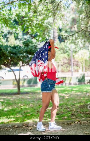 Photo arrière d'une femme de latina portant le drapeau des États-Unis à l'extérieur Banque D'Images