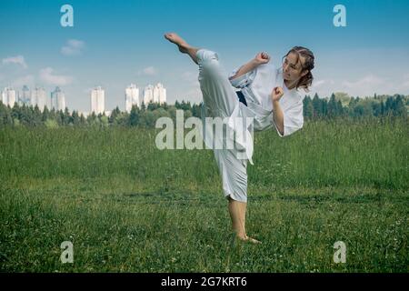 adolescente pratiquant le karaté kata à l'extérieur, exécute le uro mawashi geri (crochet de coup) Banque D'Images