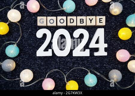 Adieu 2024 lettre de l'alphabet décorer avec boule de coton LED sur fond de tissu tricoté bleu Banque D'Images