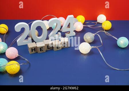 Bonjour 2024 lettre de l'alphabet et réveil décorer avec boule de coton LED sur fond bleu et rouge Banque D'Images