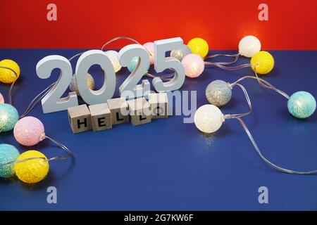 Bonjour 2025 lettre de l'alphabet et réveil décorer avec boule de coton LED sur fond bleu et rouge Banque D'Images