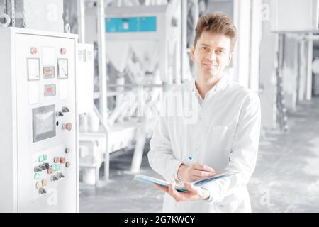 Un ingénieur opérateur de sexe masculin vérifie la ligne de production des commandes à partir du panneau de commande, usine alimentaire. Banque D'Images