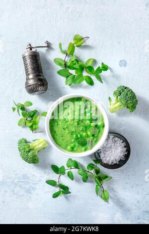 Soupe verte végétalienne avec ingrédients, dose de mise à plat au plafond. Brocoli, pois verts, menthe, sel et poivre, cuisine biologique saine, alimentation à base de plantes Banque D'Images