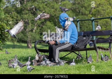 Northampton, Royaume-Uni. 15 juillet 2021. Gary Stone un lad local nourrissant les pigeons de report à Abington Park. Crédit : Keith J Smith./Alamy Live News Banque D'Images