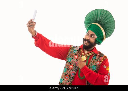 Un homme à Bhangra Costume prenant un selfie dans son téléphone. Banque D'Images