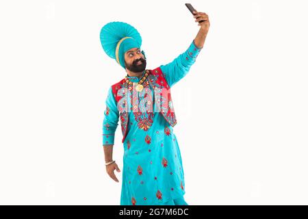 Un homme à Bhangra Costume prenant un selfie dans son téléphone. Banque D'Images