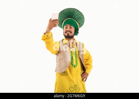 Un homme à Bhangra Costume prenant un selfie dans son téléphone. Banque D'Images