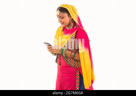 Une femme en costume de Giddha regardant dans son téléphone. Banque D'Images