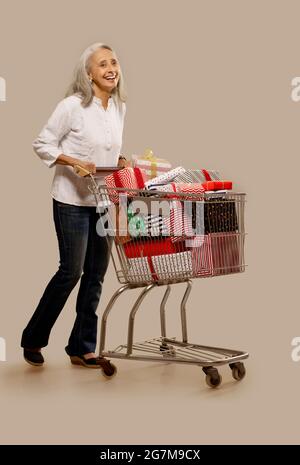 Une vieille femme heureuse debout près de son panier plein de cadeaux. Banque D'Images