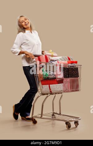 Une vieille femme heureuse debout près de son panier plein de cadeaux. Banque D'Images