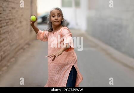 Une vieille femme jouant au cricket Bowling. Banque D'Images